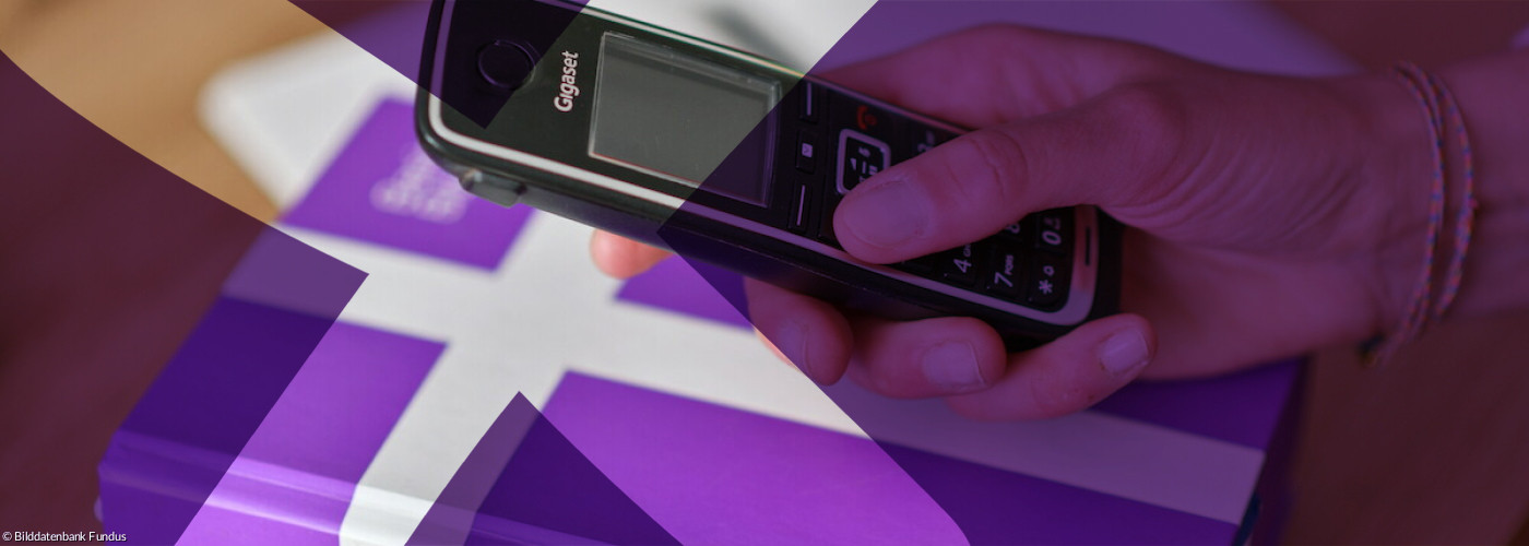 Hand mit Telefon über Bibel